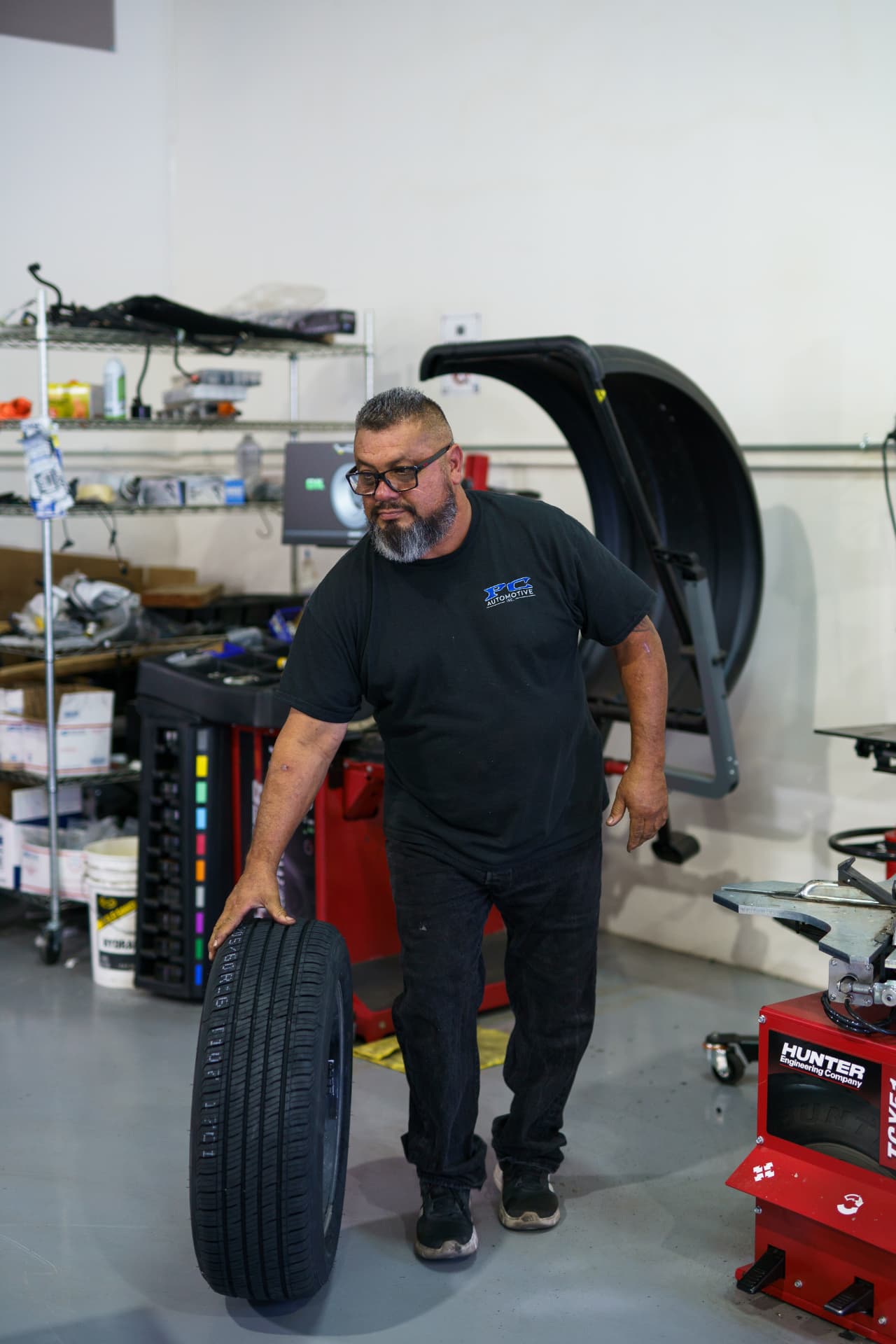 PC Automotive technician rolling a tire to the mounting machine