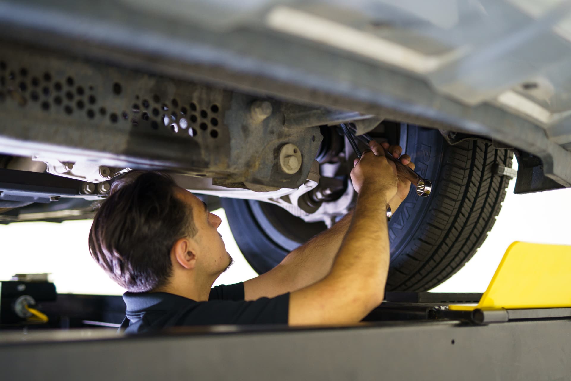 Technician working underneath a vehicle on the lift