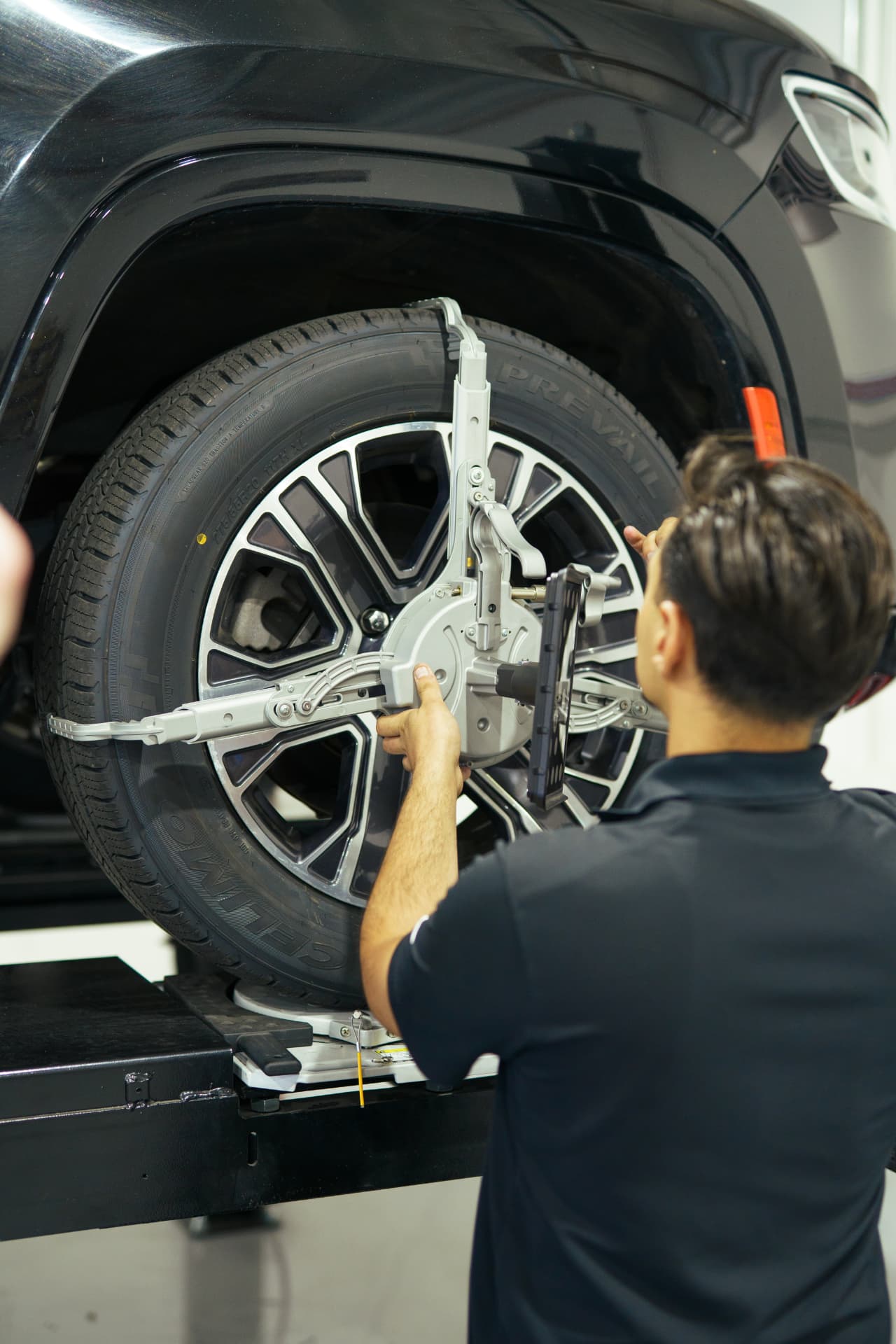 Technician mounting alignment sensors on a wheel at PC Automotive